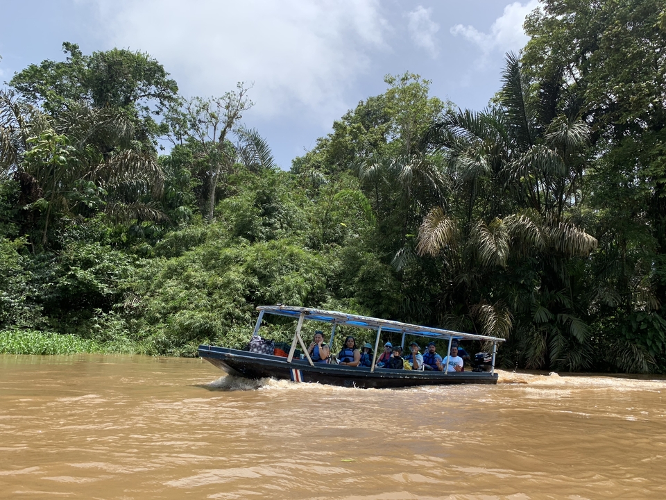 Des touristes sur un bateau naviguant sur une rivière tropicale.