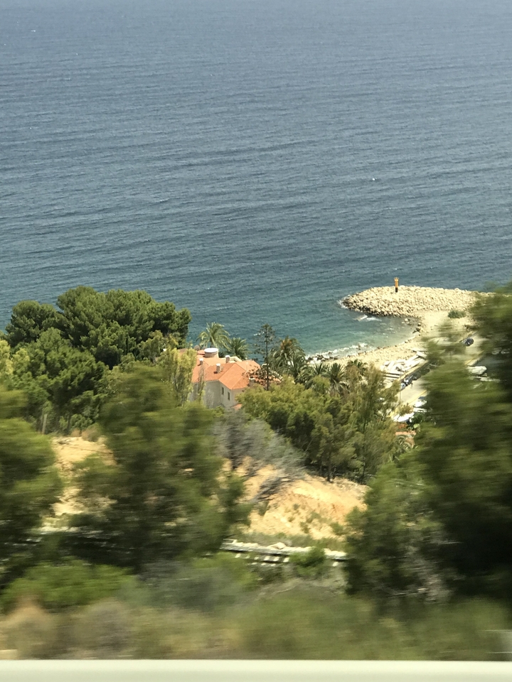 Vue côtière avec une maison, des arbres et la mer.