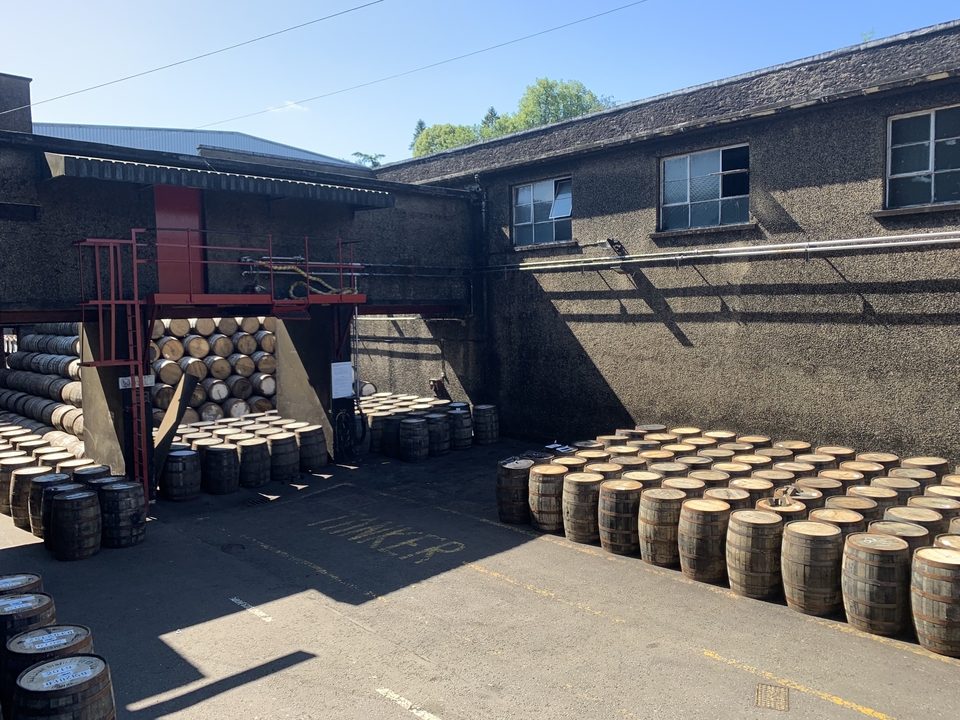 Barils de whisky empilés dans une distillerie en plein air.