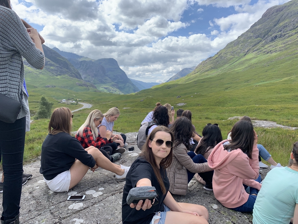 Groupe de personnes assises sur un rocher avec un paysage montagneux.