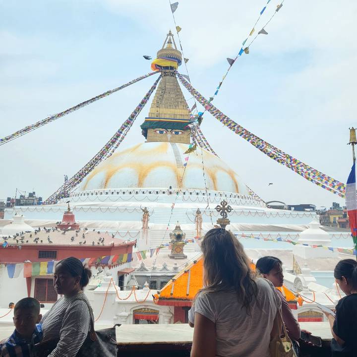 People viewing a large stupa with prayer flags.