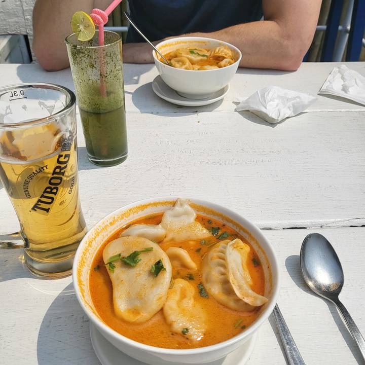 A bowl of dumplings in a creamy orange sauce on a table.