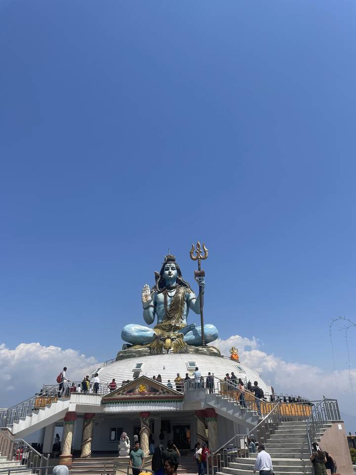 Grande statue de Shiva sur un toit avec un ciel dégagé.