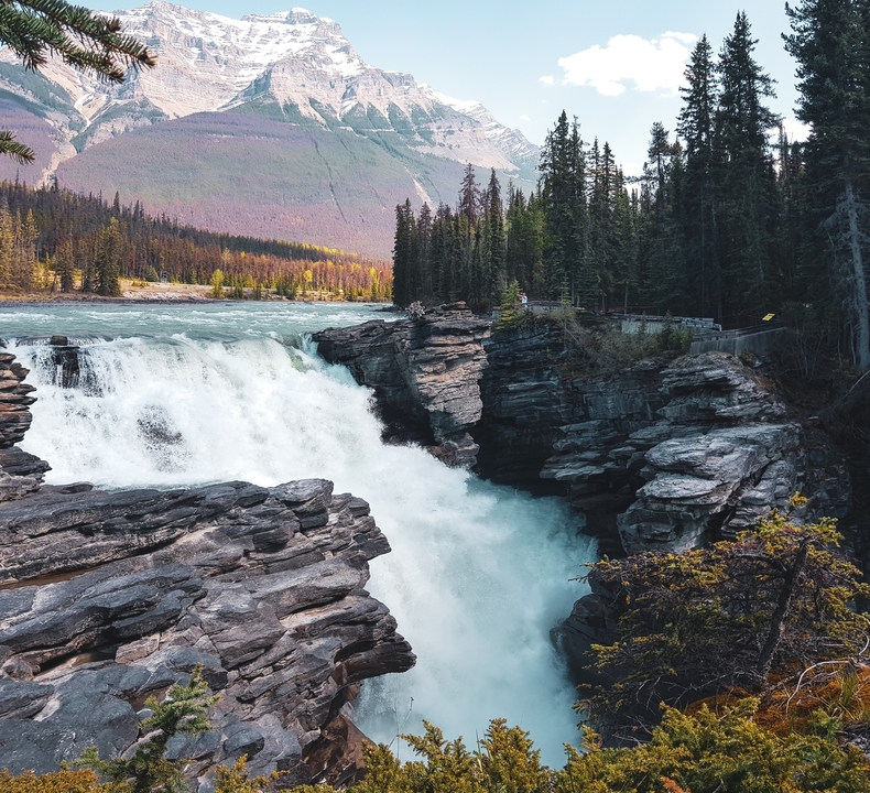 Cascade pittoresque entourée de falaises rocheuses et de forêt.
