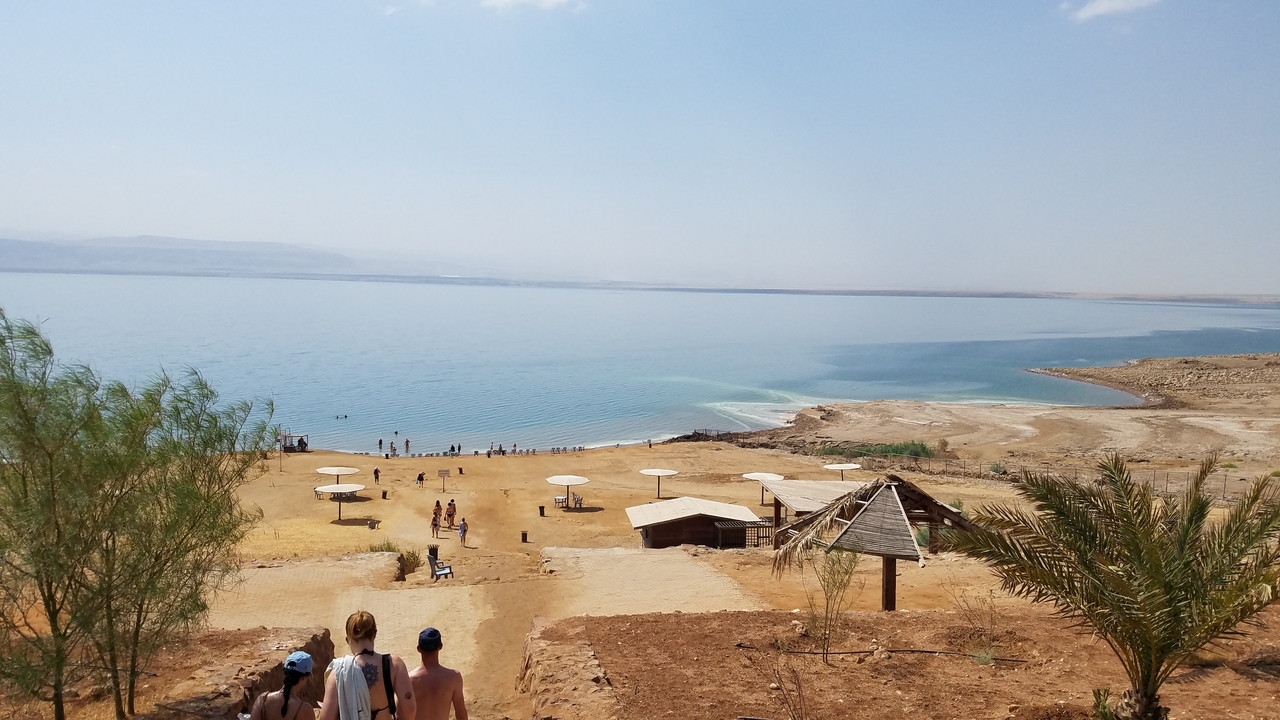 Des gens surplombant la mer Morte sous un ciel dégagé.