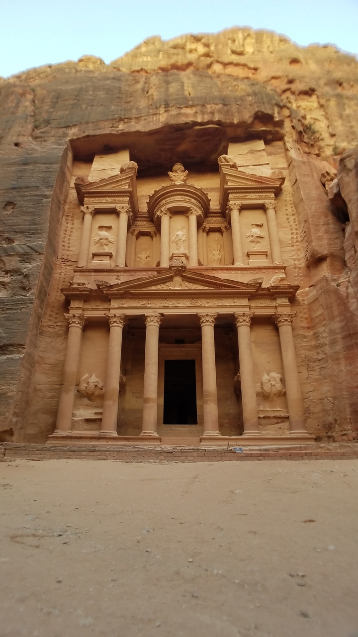 Here's the French translation:
"La façade du Trésor de Pétra sculptée dans la paroi rocheuse."
Alternative translation:
"La façade du Trésor de Pétra taillée dans la falaise."