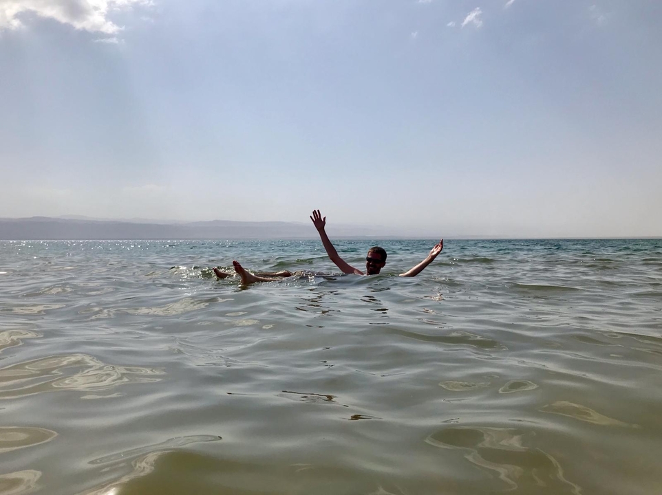 Personne flottant dans la mer Morte avec les bras levés.