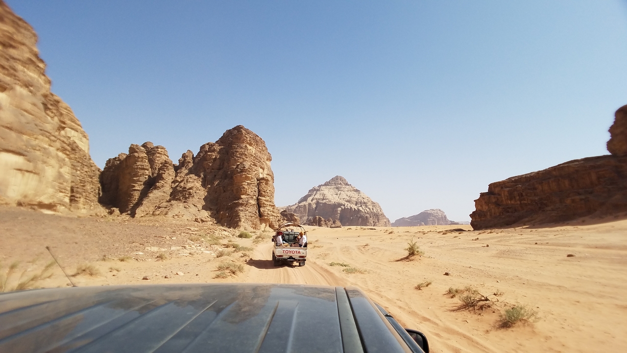 Jeep roulant à travers un paysage désertique avec des falaises rocheuses.