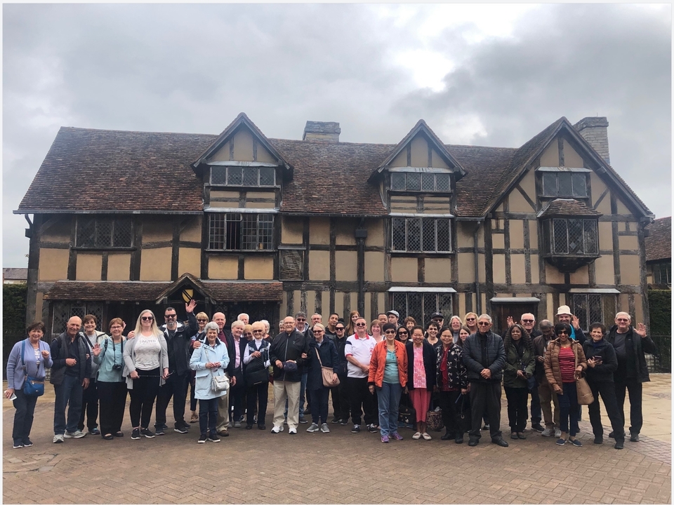 Un groupe de touristes posant devant une maison historique à colombages.