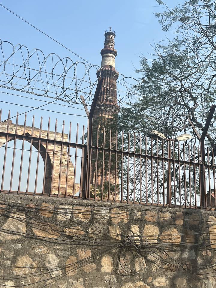 Vue du Qutub Minar à travers une clôture.