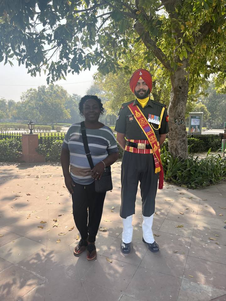 Personne posant avec un garde sous les arbres.