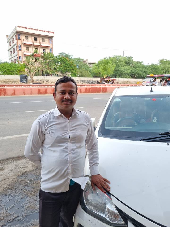 Homme debout près d'un véhicule avec un bâtiment en arrière-plan.