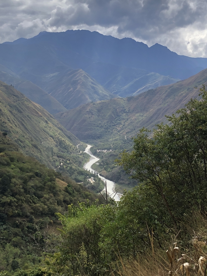 Vallée avec une rivière sinueuse entourée de montagnes vertes.