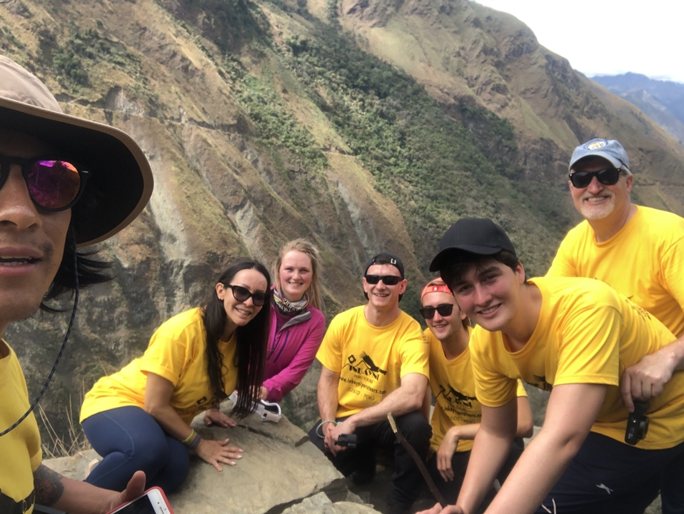 Groupe de randonneurs posant sur un sentier de montagne avec un paysage de hautes terres en arrière-plan.