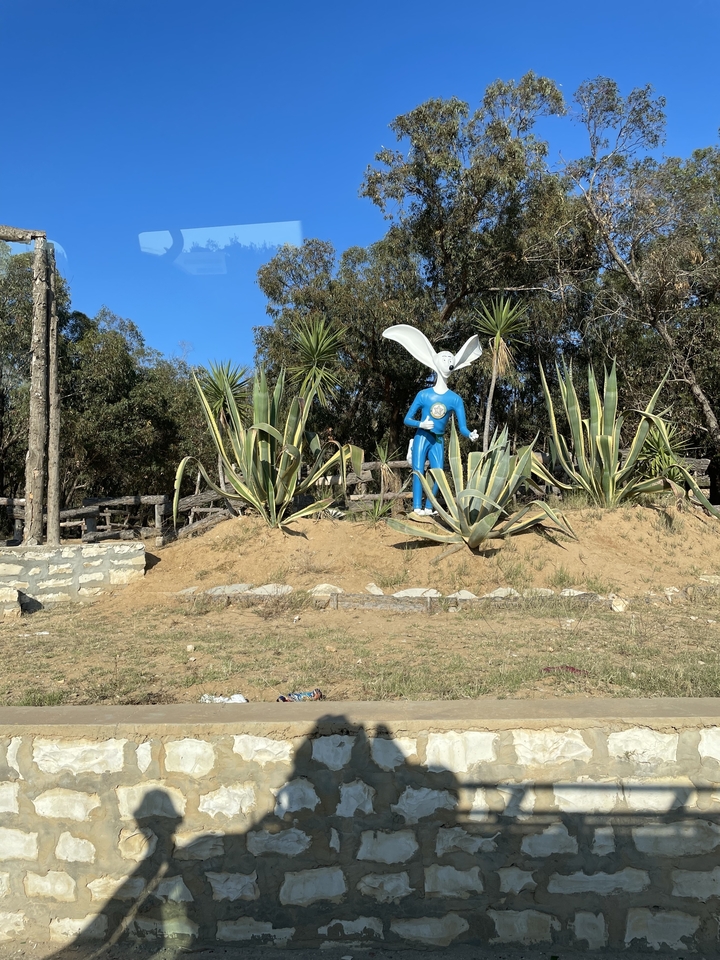 Une statue d'un homme-lapin au milieu de la verdure.