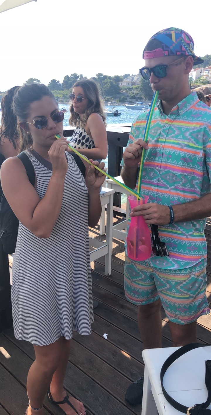 Deux personnes debout qui partagent une boisson avec une longue paille.