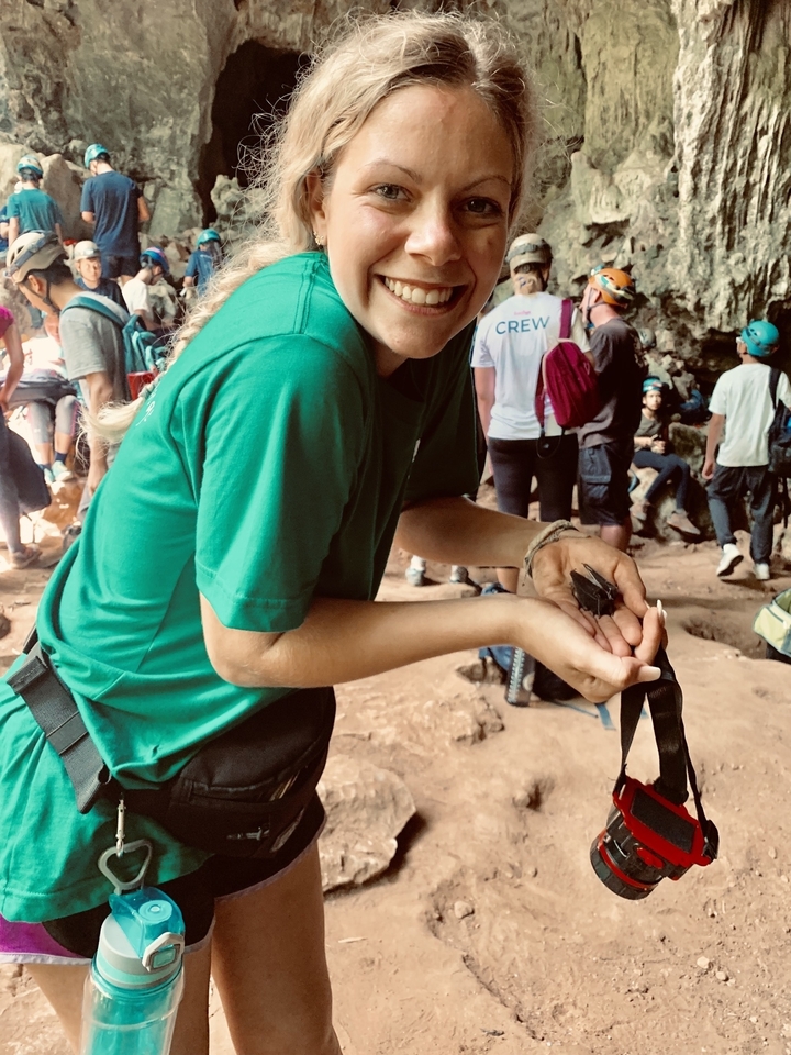 Personne tenant une chauve-souris dans ce qui semble être une grotte.