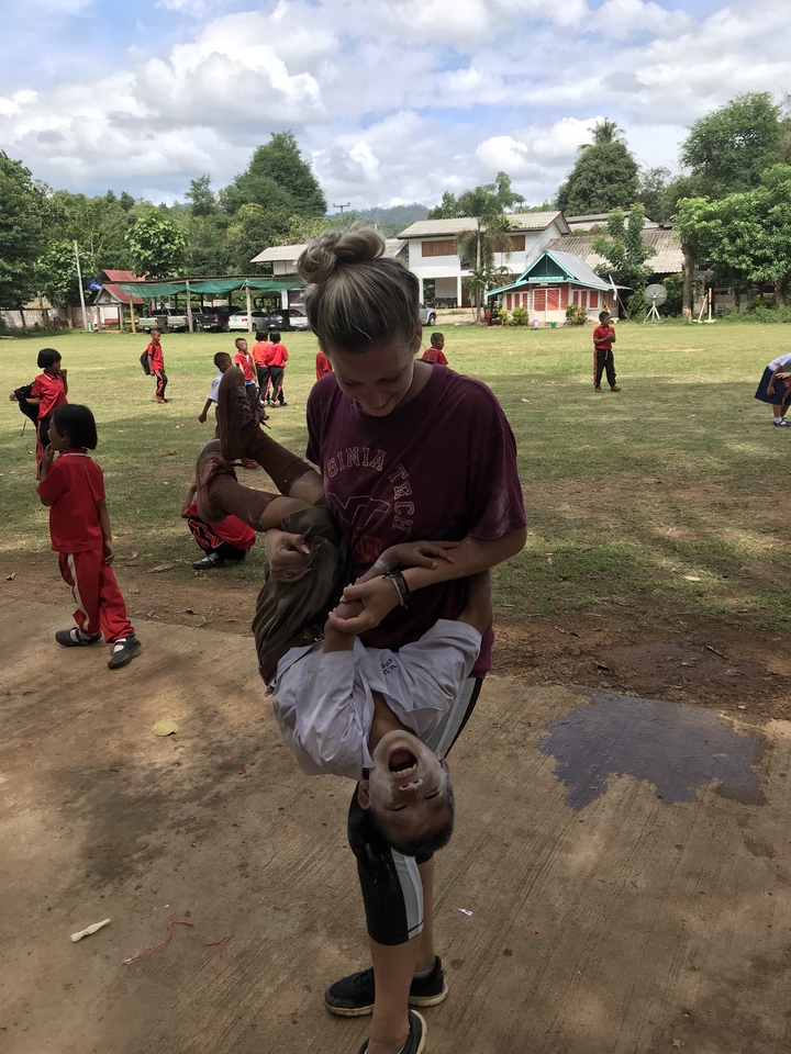 Femme tenant un enfant enjoué, entourée d'autres enfants.