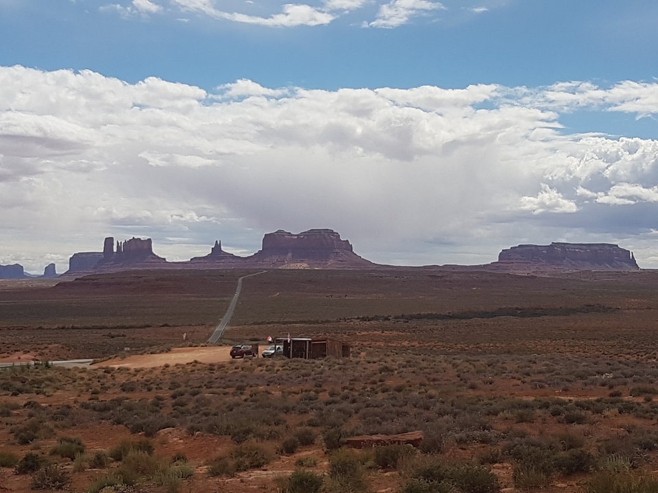 Vue panoramique de Monument Valley avec une route au loin.