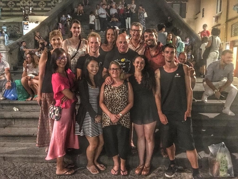 Groupe de personnes souriantes sur des marches en pierre, probablement dans un environnement urbain.