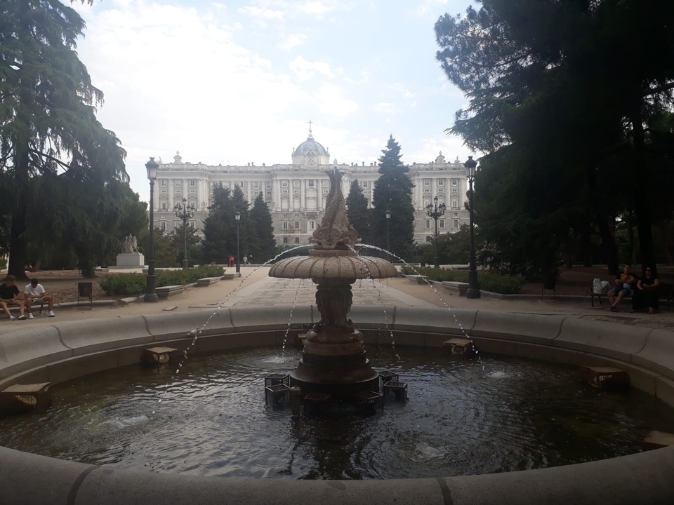 Une fontaine dans un parc devant un grand bâtiment historique.