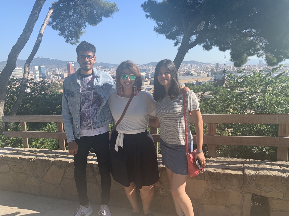 Trois personnes posant avec un paysage urbain pittoresque en arrière-plan.