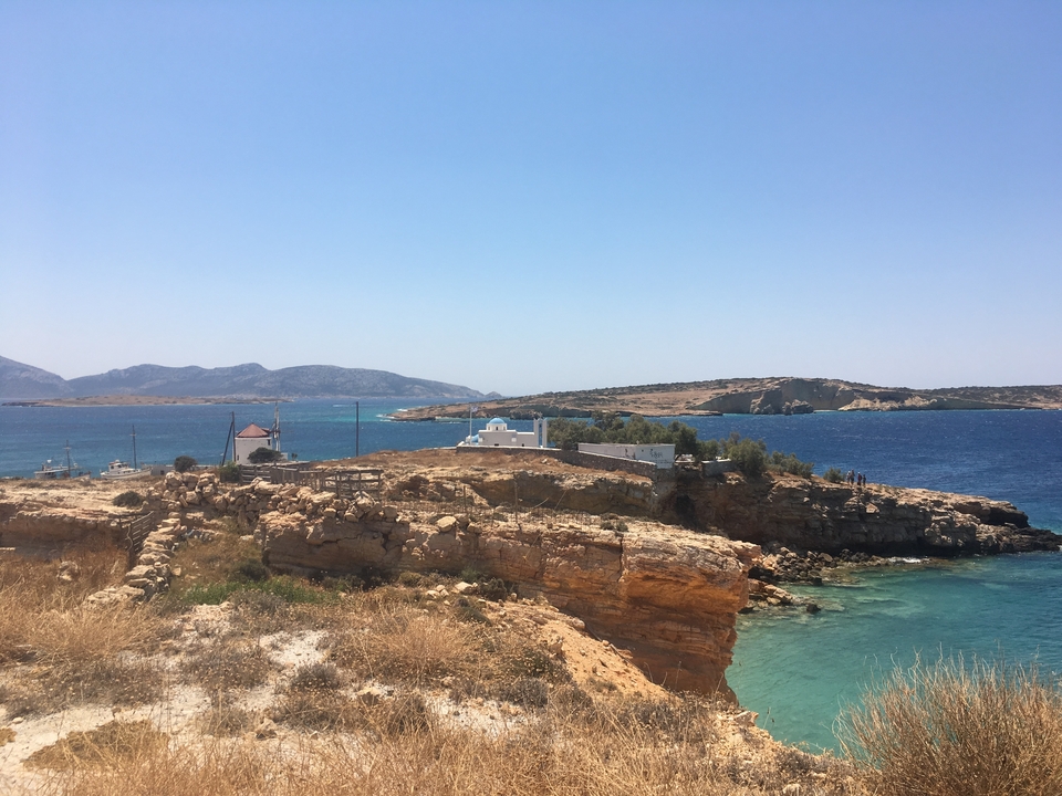 Vue côtière avec un terrain rocheux et une île en arrière-plan.