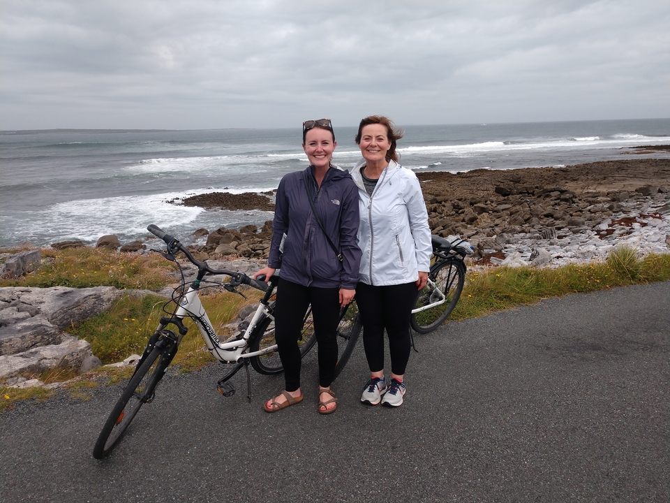Deux femmes posant avec des vélos sur une route côtière.