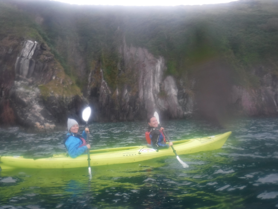 Deux personnes faisant du kayak devant des falaises rocheuses.