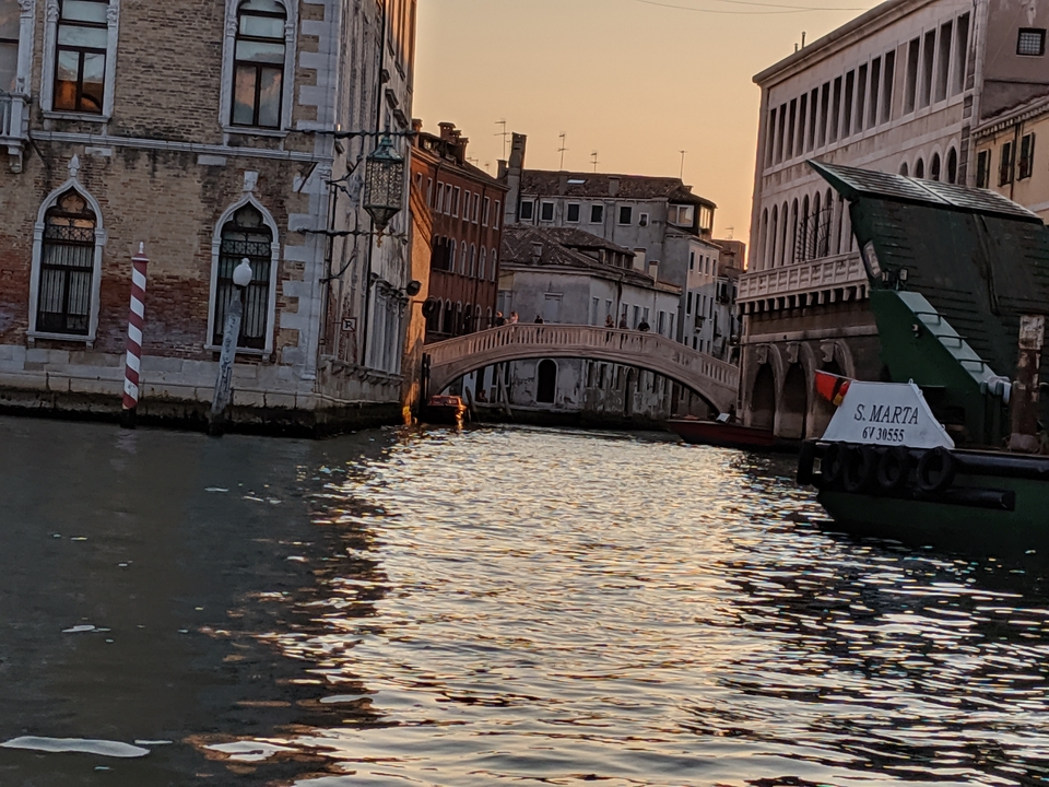 Canal vénitien au coucher du soleil avec un petit pont.