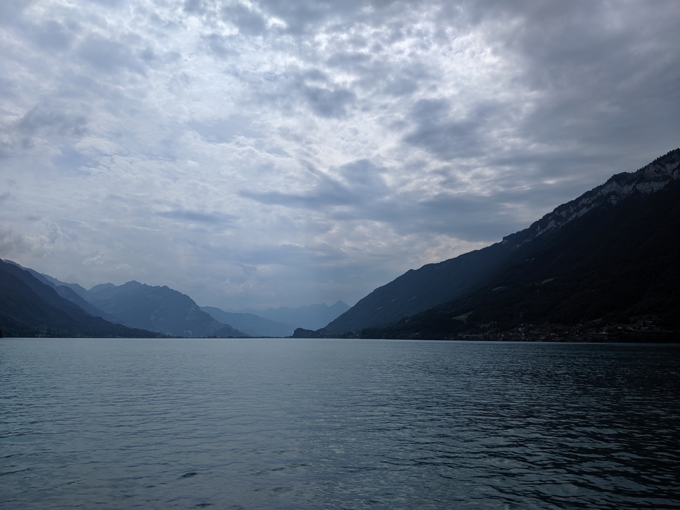 Vue d'un lac avec des montagnes sous un ciel nuageux.