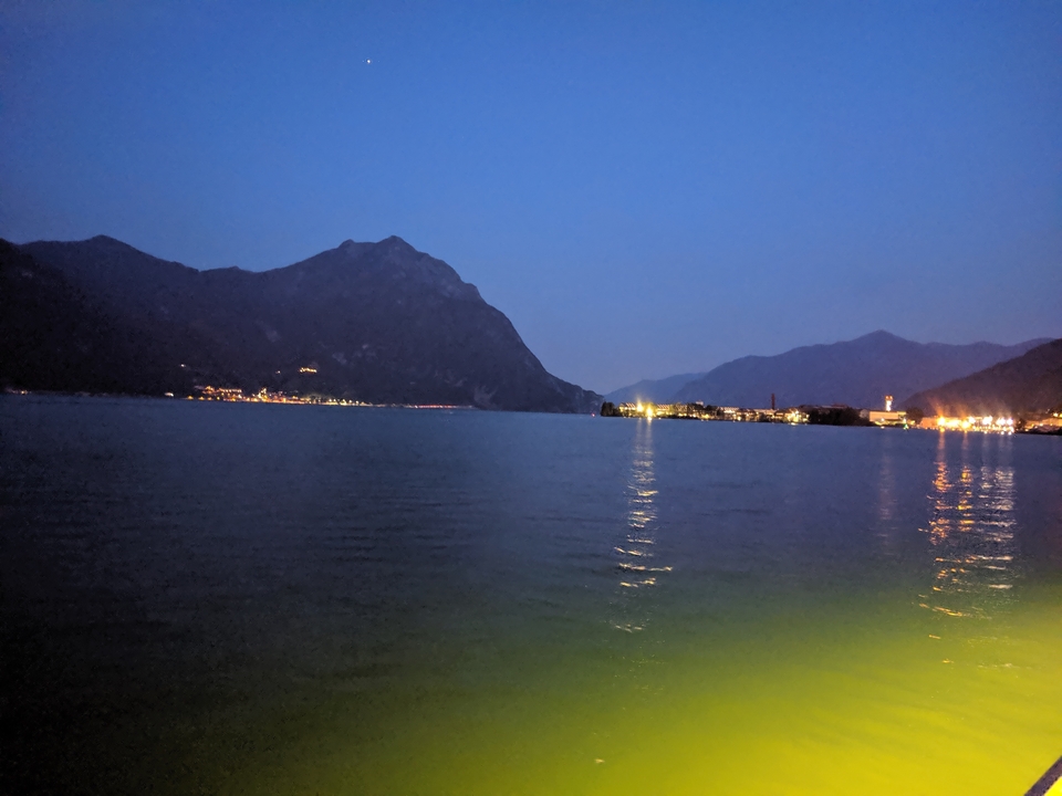 Vue nocturne d'un lac avec les lumières lointaines de la ville.