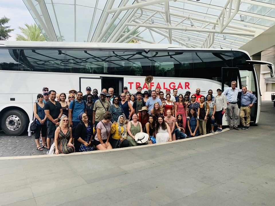 Photo de groupe devant un autocar de tourisme portant l'inscription « Trafalgar ».