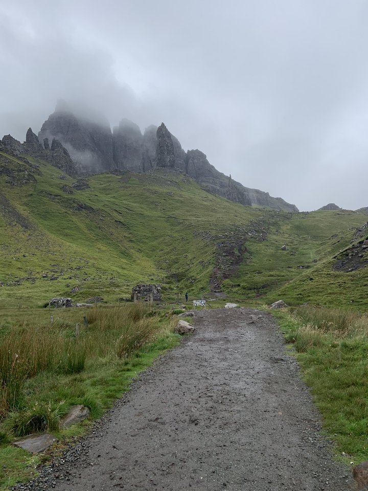 A rugged landscape with green hills and a pathway leading upwards.