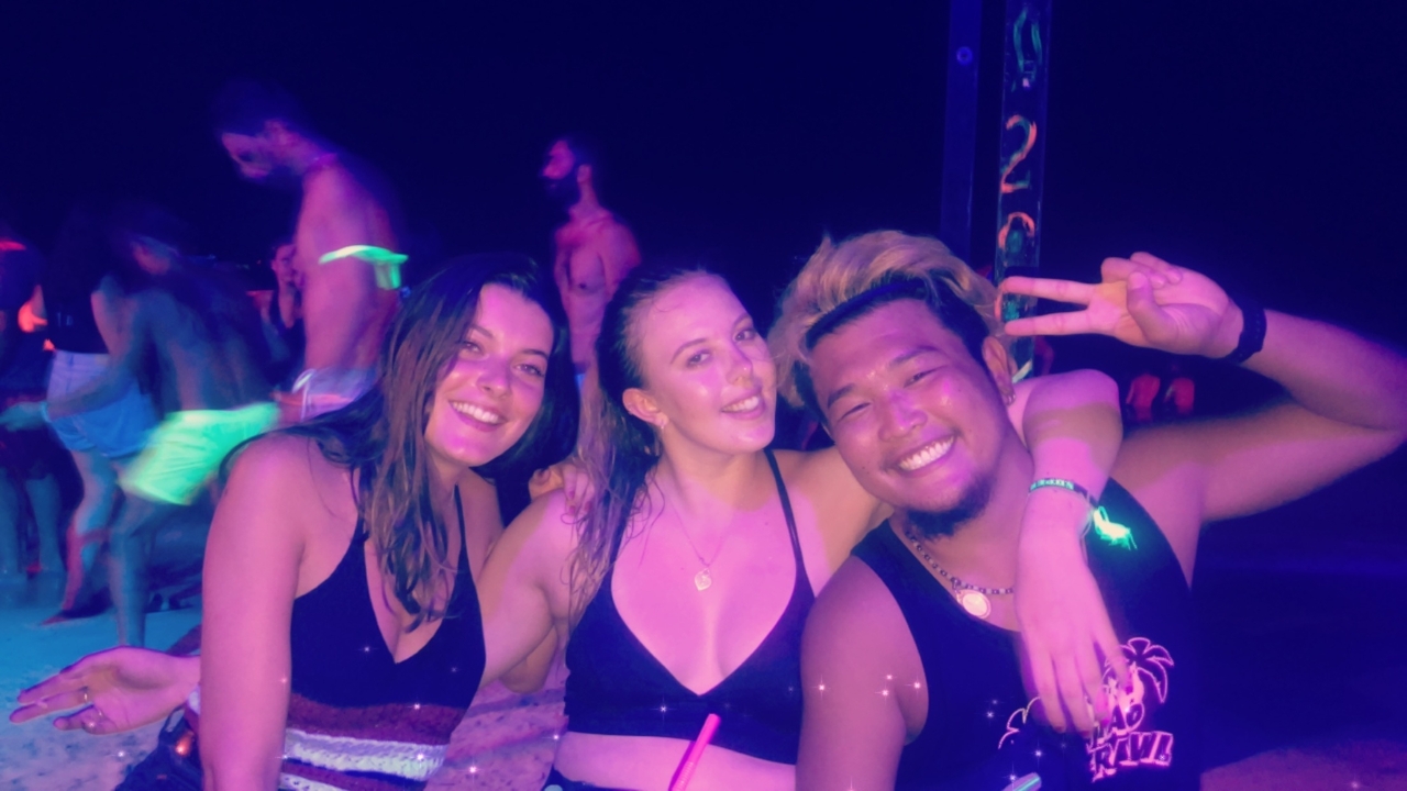 Groupe d'amis qui posent sur une plage la nuit avec des décorations lumineuses.