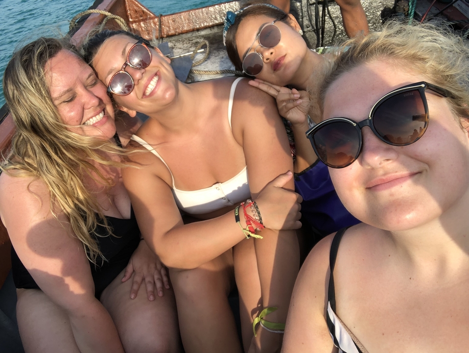 Un groupe d'amis prenant un selfie joyeux sur un bateau.