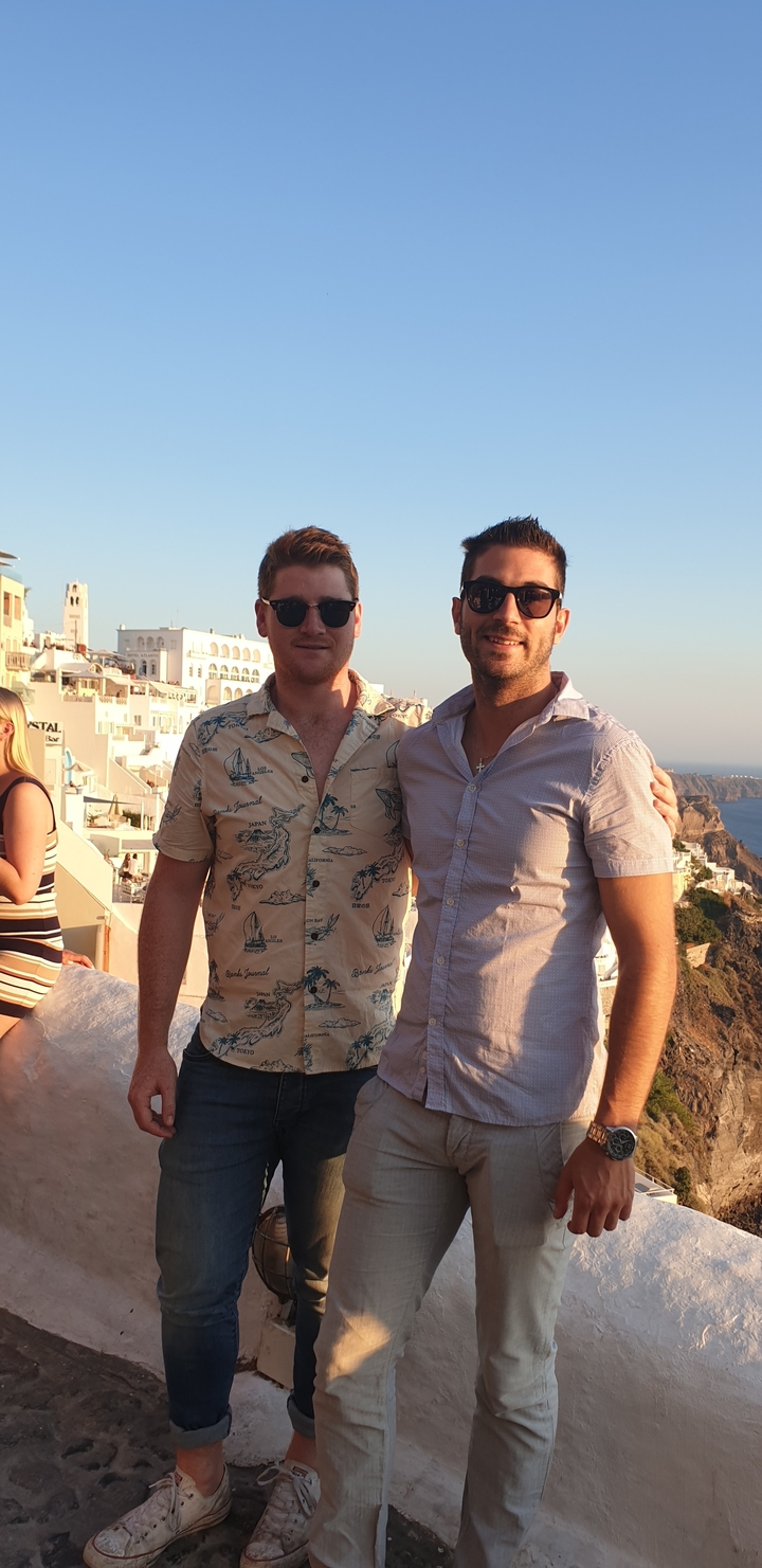 Deux hommes posant avec une vue côtière en arrière-plan.