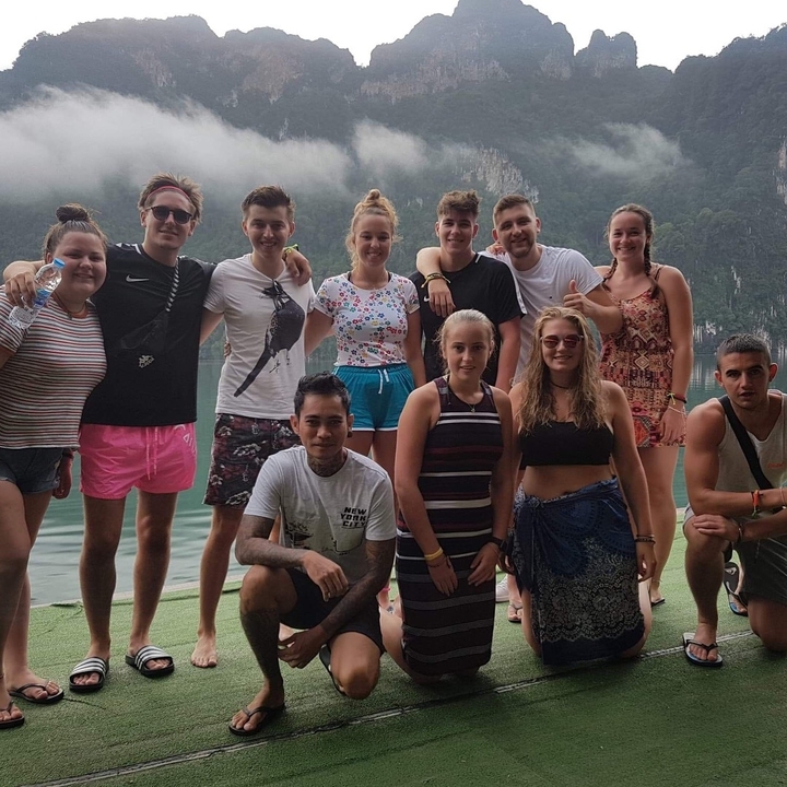 Group of young travelers posing by a scenic lake.