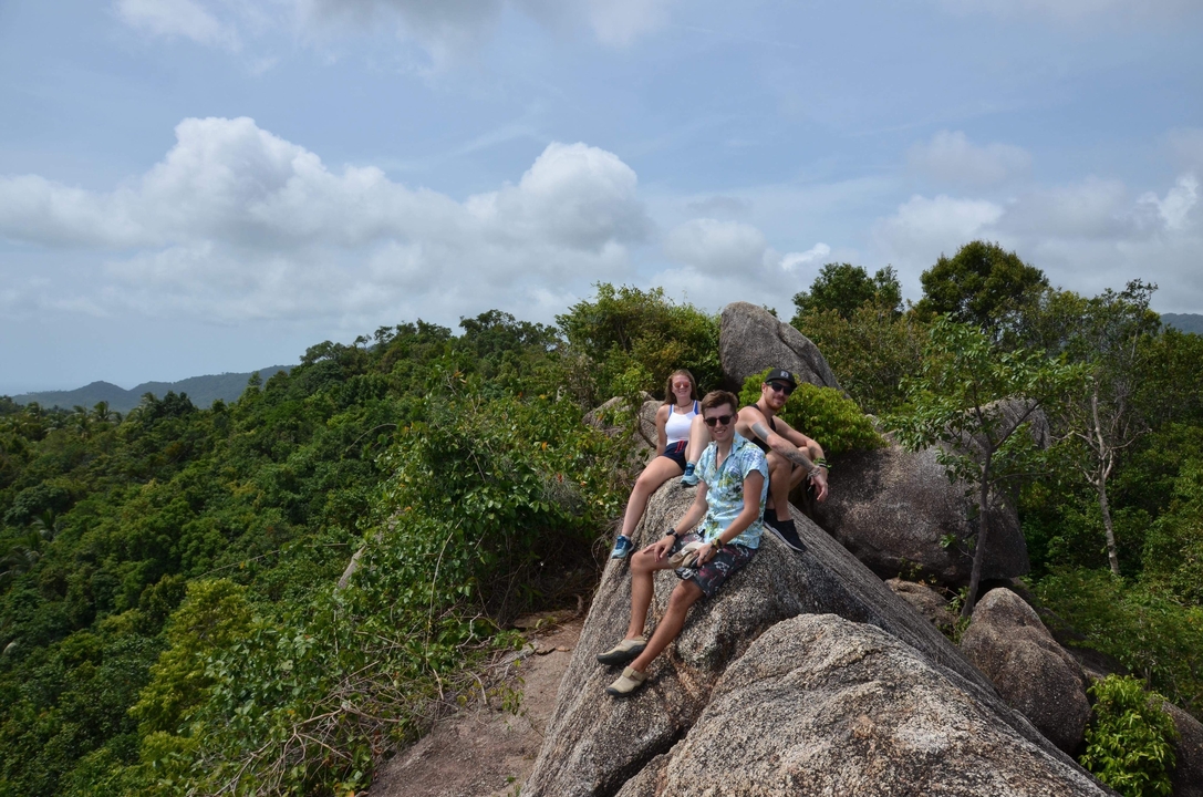 Travelers sitting on large rocks with a lush landscape backdrop.