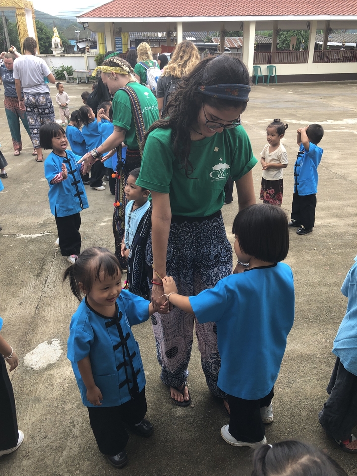 Femme tenant la main d'enfants en uniforme scolaire à l'extérieur.