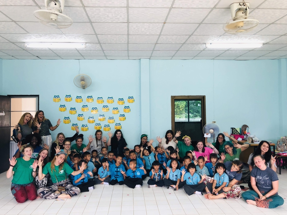Groupe de personnes posant à l'intérieur avec des enfants en uniforme scolaire.