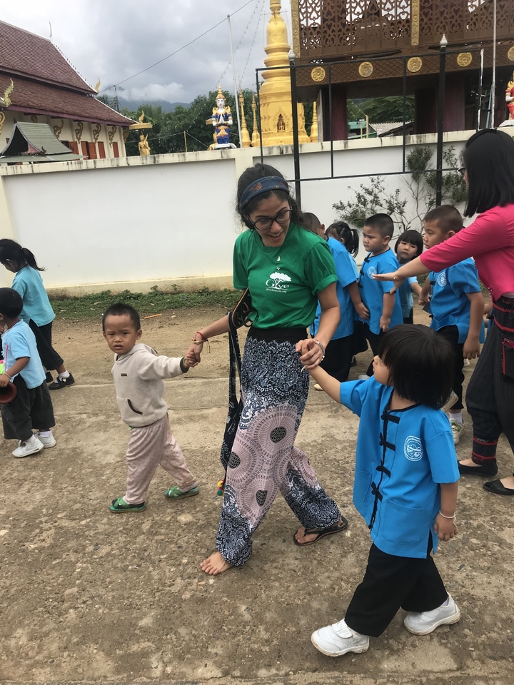 Femme tenant la main d'enfants en uniforme scolaire à l'extérieur.