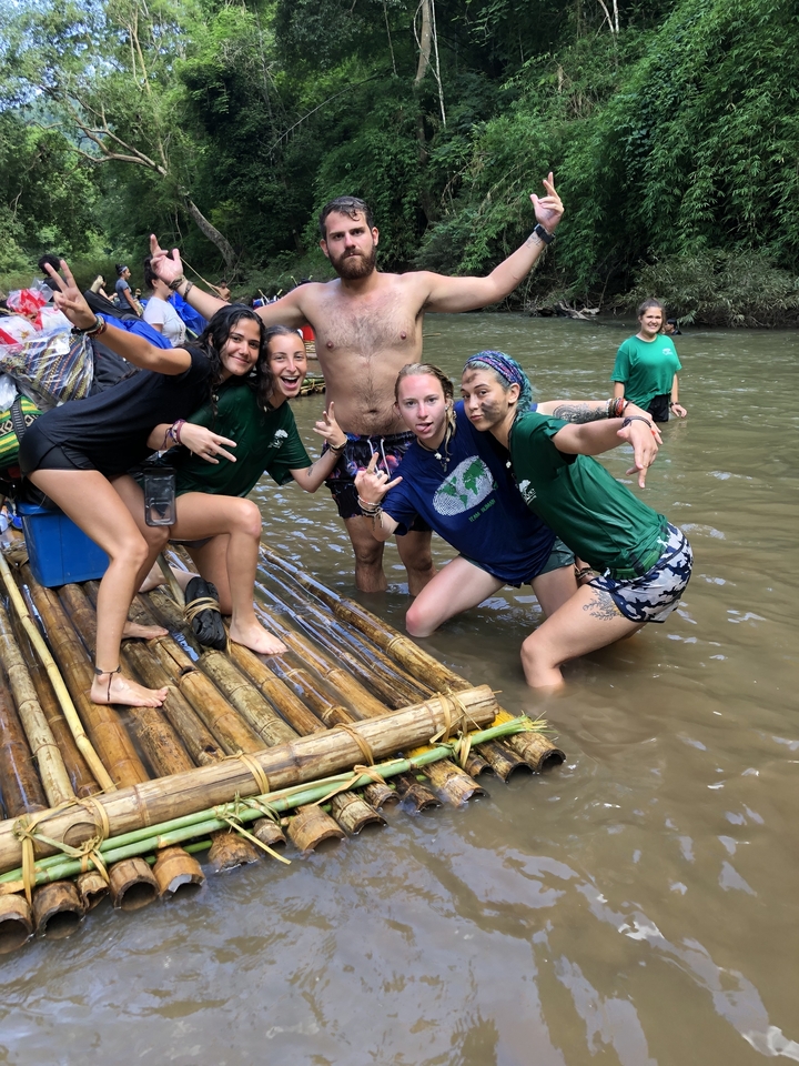 Groupe de personnes posant sur un radeau de bambou dans une rivière.