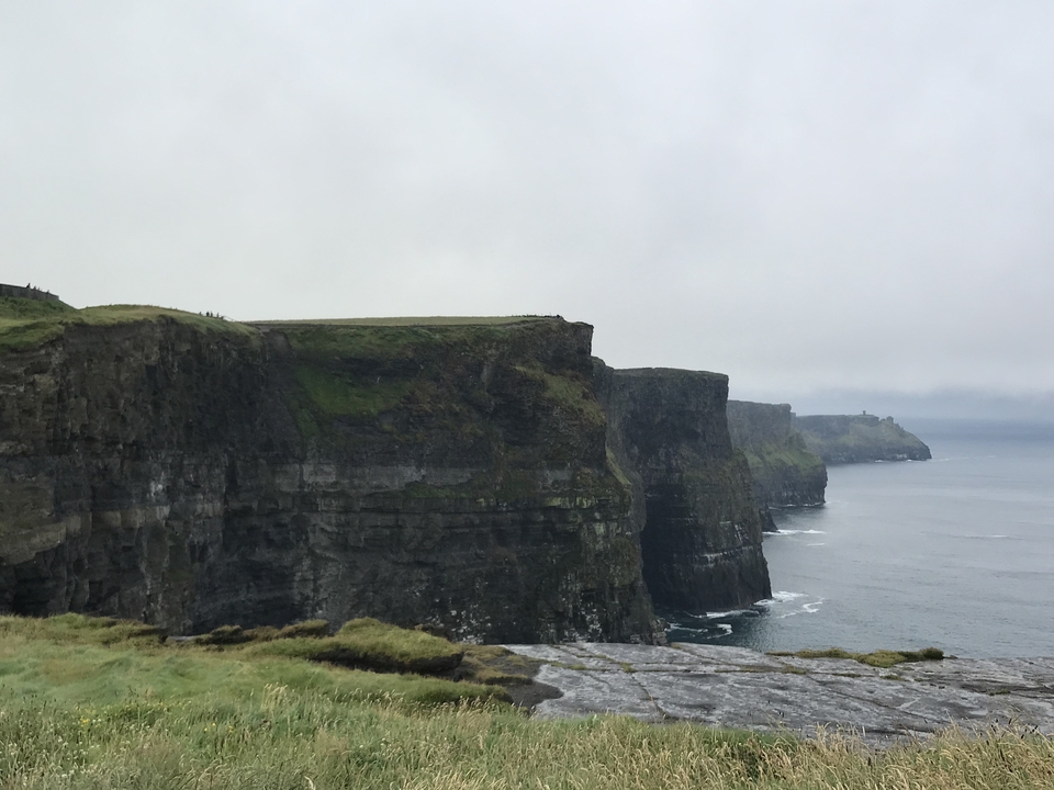 Les falaises spectaculaires de Moher surplombant l'océan sous un ciel nuageux.