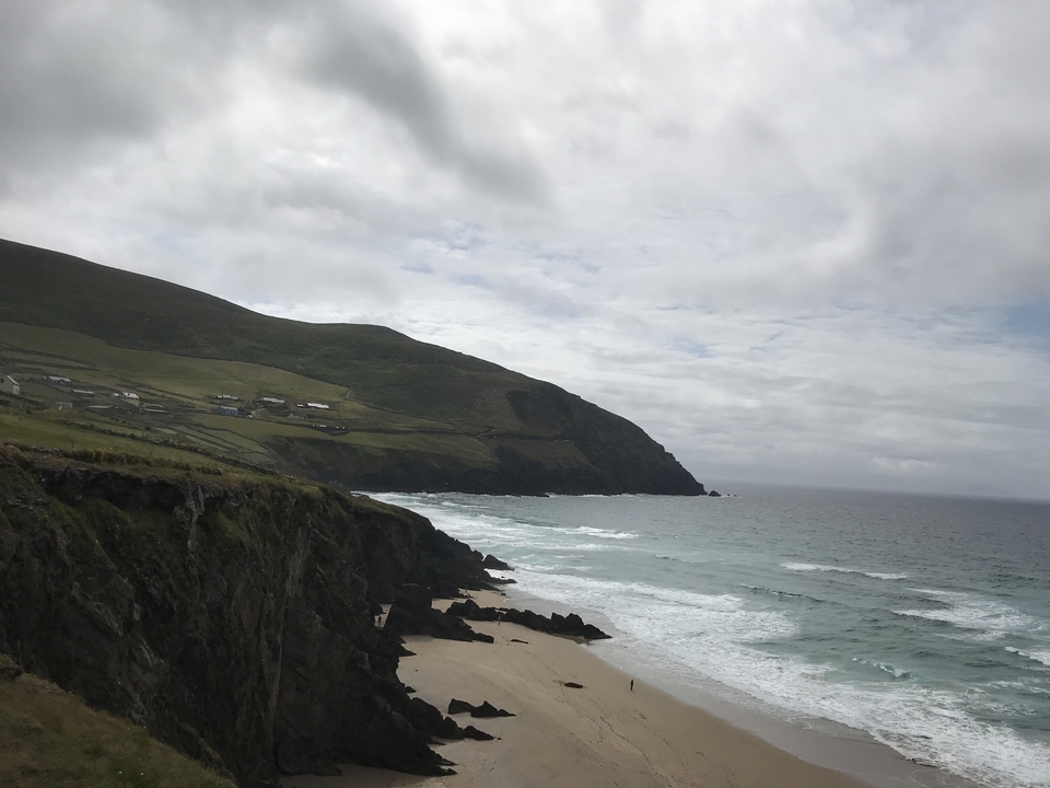 Une côte escarpée avec des vagues qui se brisent sur les falaises sous un ciel nuageux.