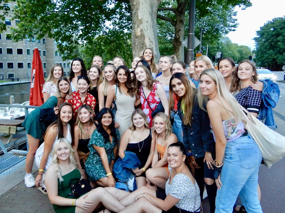 Un grand groupe de jeunes gens posant pour une photo à l'extérieur.