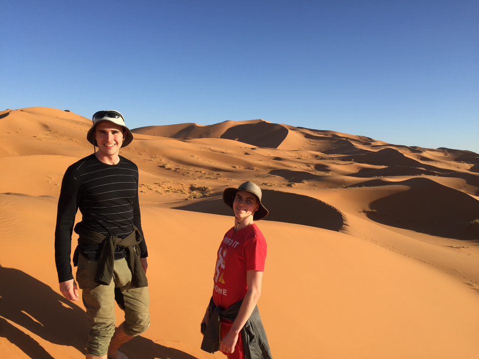 Deux personnes debout dans un paysage désertique avec des dunes de sable.
