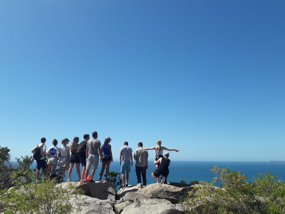 Un groupe de personnes debout sur une falaise avec l'océan en arrière-plan.