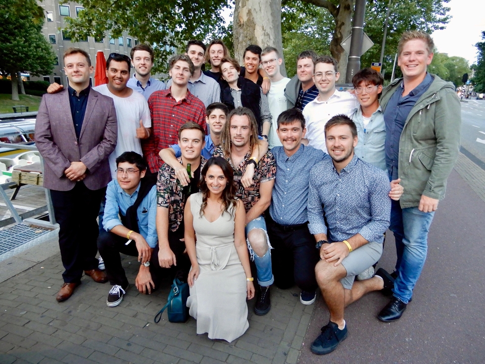 Un grand groupe de personnes posant avec un décor de rue en arrière-plan.