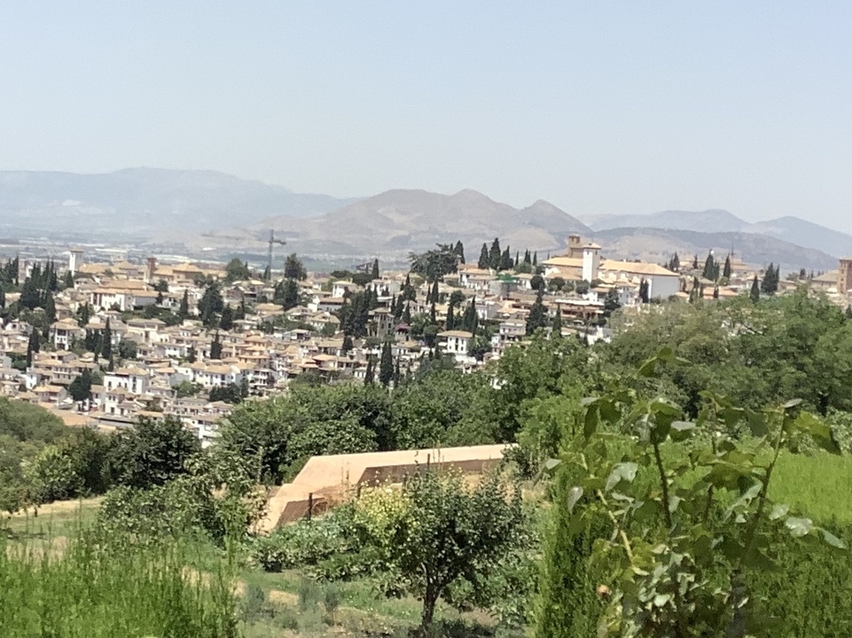 Vue panoramique d'une ville avec des bâtiments et un arrière-plan montagneux.